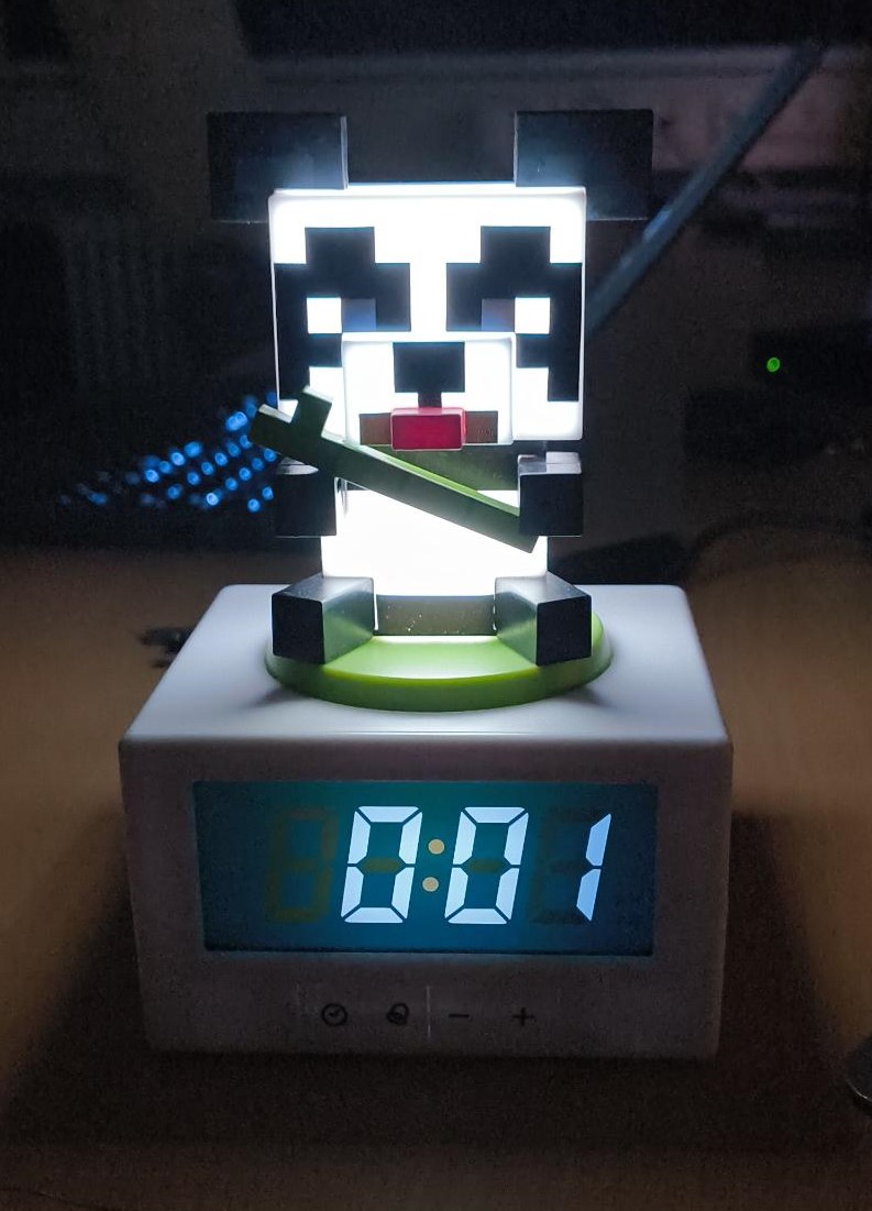 A glowing panda sitting on top of an alarm clock